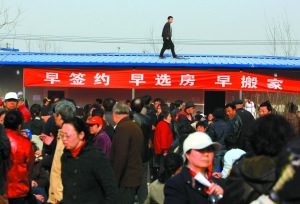 2010年4月,通州新华北路拆迁签约点,一工作人员在房顶上准备安装线路,他下方是等候签署拆迁安置协议的居民。本报资料图片 周晓东 摄 2010年4月,通州新华北路拆迁签约点,一工作人员在房顶上准备安装线路,他下方是等候签署拆迁安置协议的居民。本报资料图片 周晓东 摄